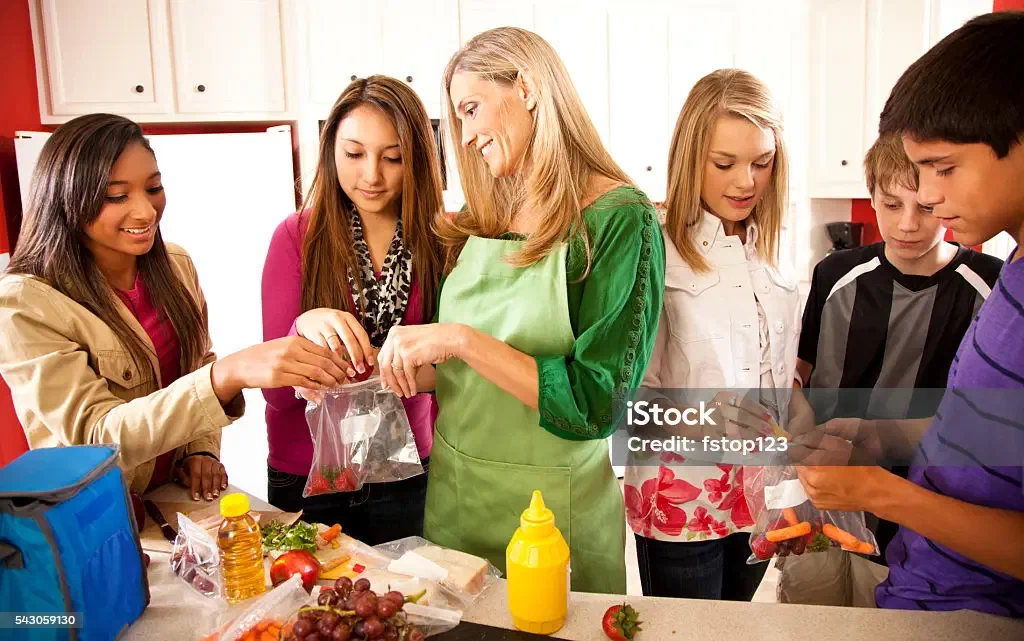 A foster mom making lunches with teens in the kitchen