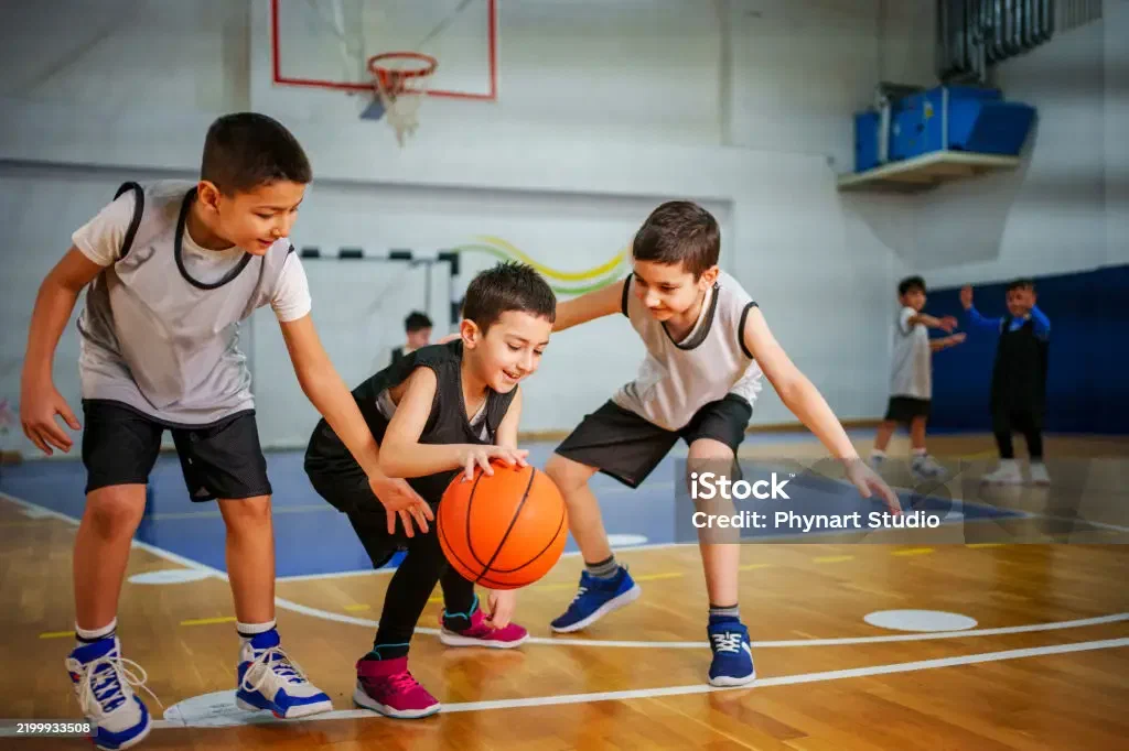 Teens playing basketball in a campus gym