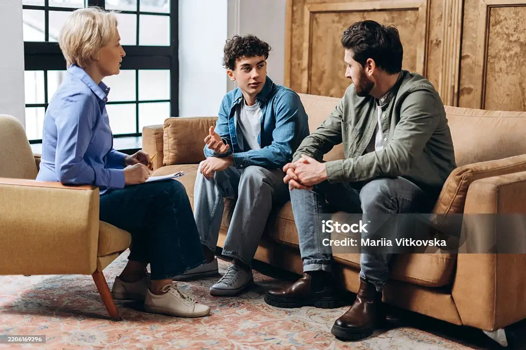 A father and teenage son talking with a therapist