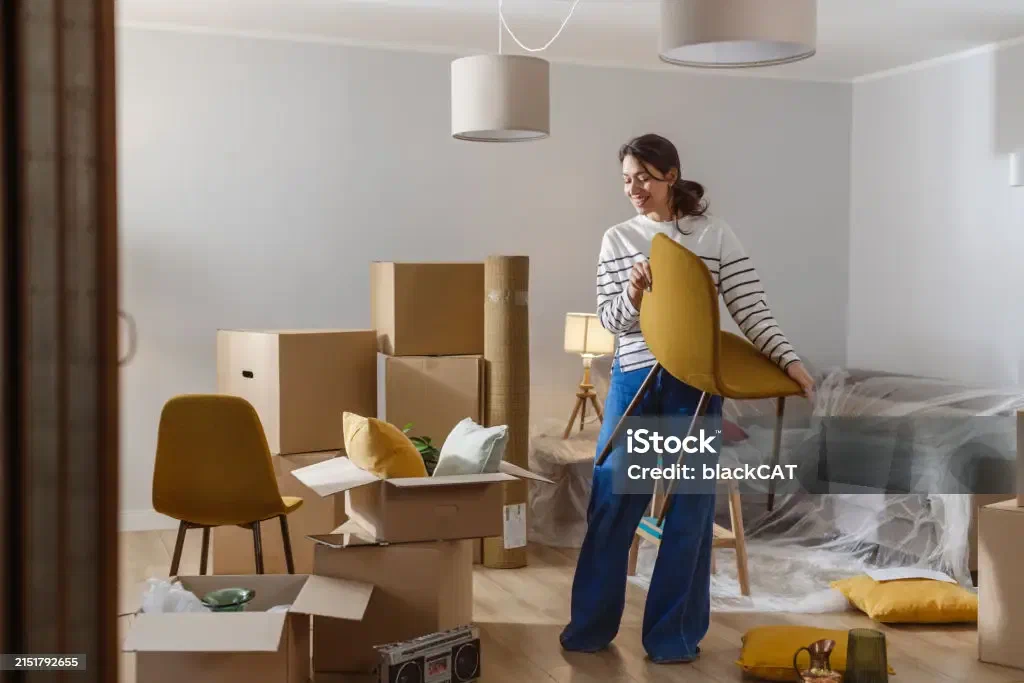 A young woman surrounded by moving boxes in her first apartment
