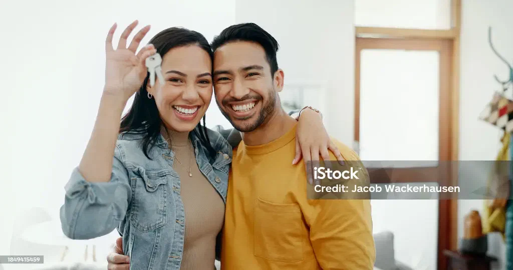 A young adult holding the keys to a new home